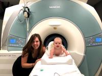 A researcher and baby in front of an fMRI scanner