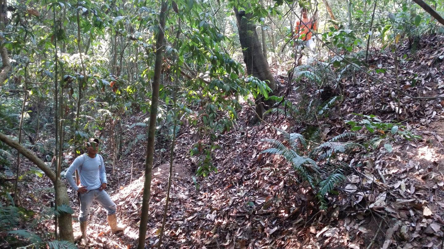 two of the crew showing the depth of a ditch, one at the top and one at base of the ditch