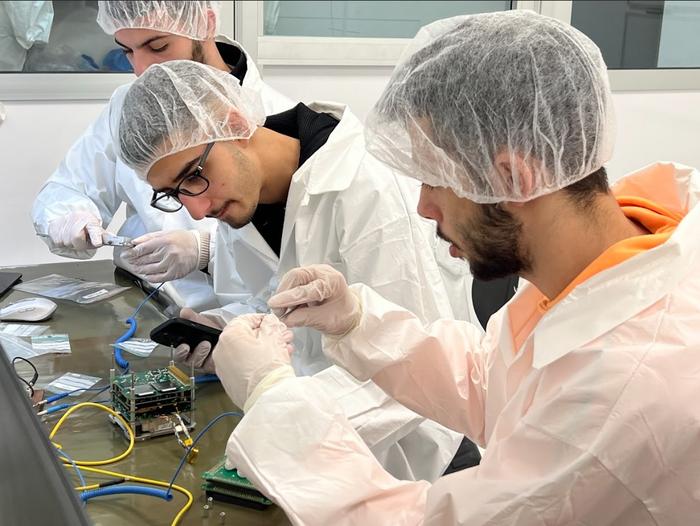 Students work on the satellite in the clean room.