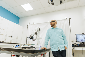 Alán Aspuru-Guzik posing with a robotic arm in The Matter Lab.