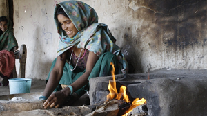 Indian woman at home preparing food by an open fire fuelled by logs