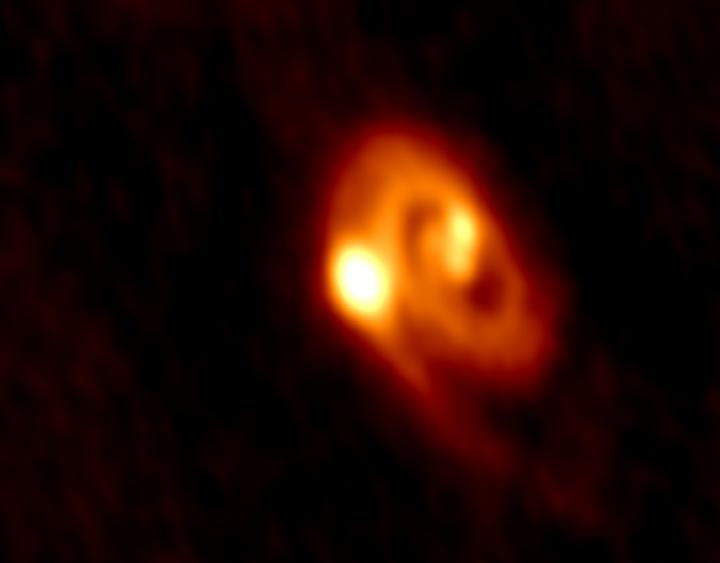 Rare Triple-Star System Surrounded by a Disk With a Spiral Structure