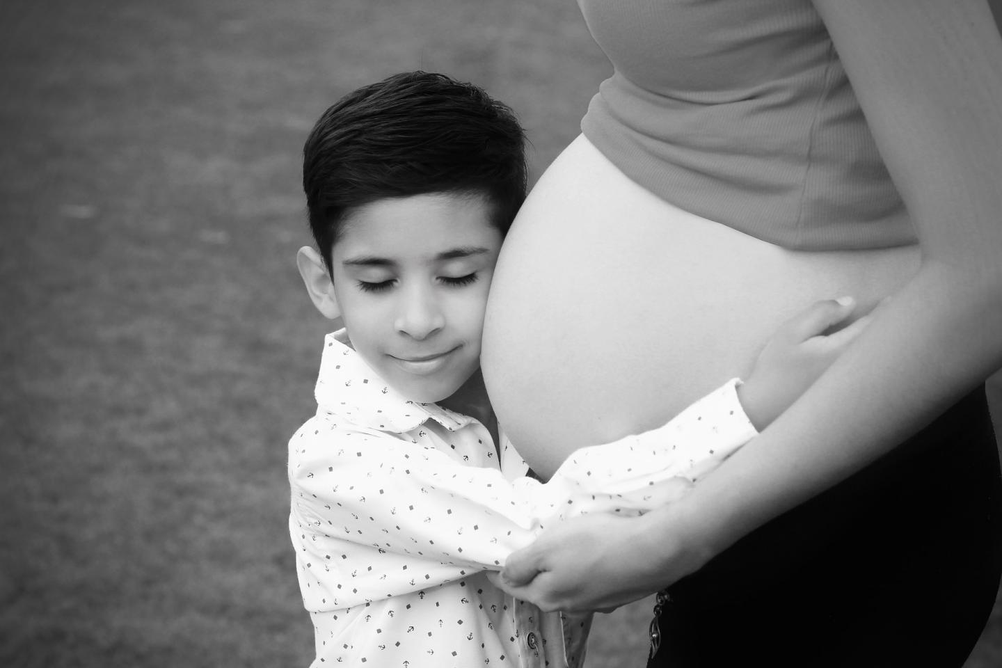 boy hugging mother's pregnant belly