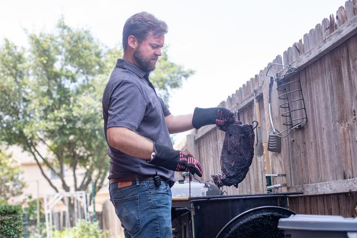 Dr. Jeremiah Gassensmith, associate professor of chemistry and biochemistry at The University of Texas at Dallas, cooks brisket in his backyard smoker.