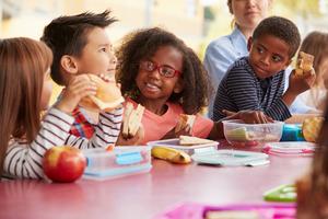 Four children eat packed lunches together.