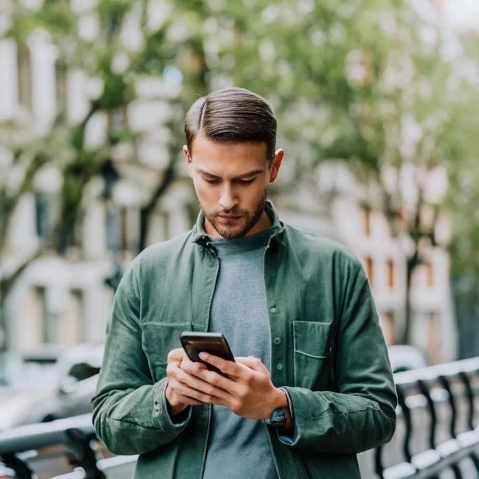 Young person consults his smartphone in the middle of the street