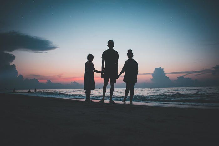 Three people standing on a beach.