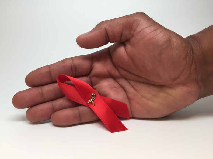 An HIV awareness ribbon in a person's hand