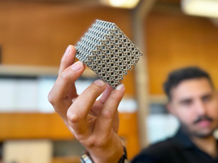 PhD candidate Jordan Noronha holding a sample of the new titanium lattice structure 3D printed in cube form. Credit: RMIT.