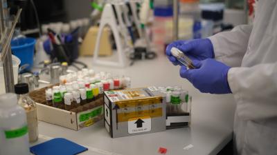 Scientist holds fruit fly vial next to box sent to ISS