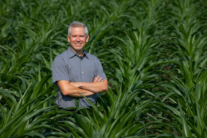 Matthew Hufford stands in a field of corn