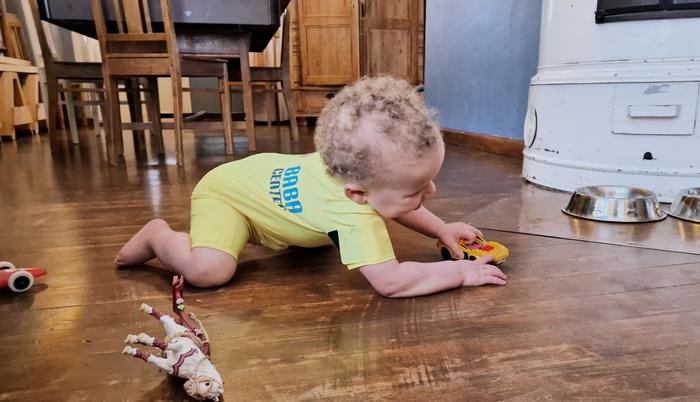 A child in smart jumpsuit playing with a toy car