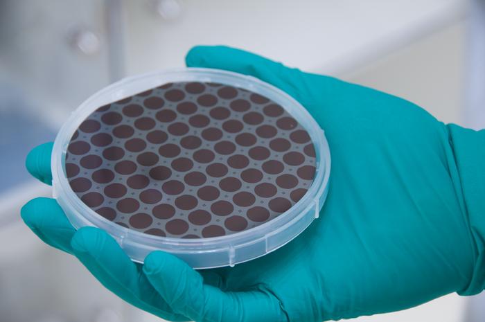 A patterned four-inch GaAs wafer with monocrystalline GaAs/AlGaAs dies that will eventually be fusion-bonded onto the coated silicon substrates.