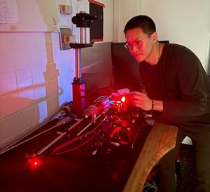 Graduate researcher Anthony Song is shown operating the optical setup.